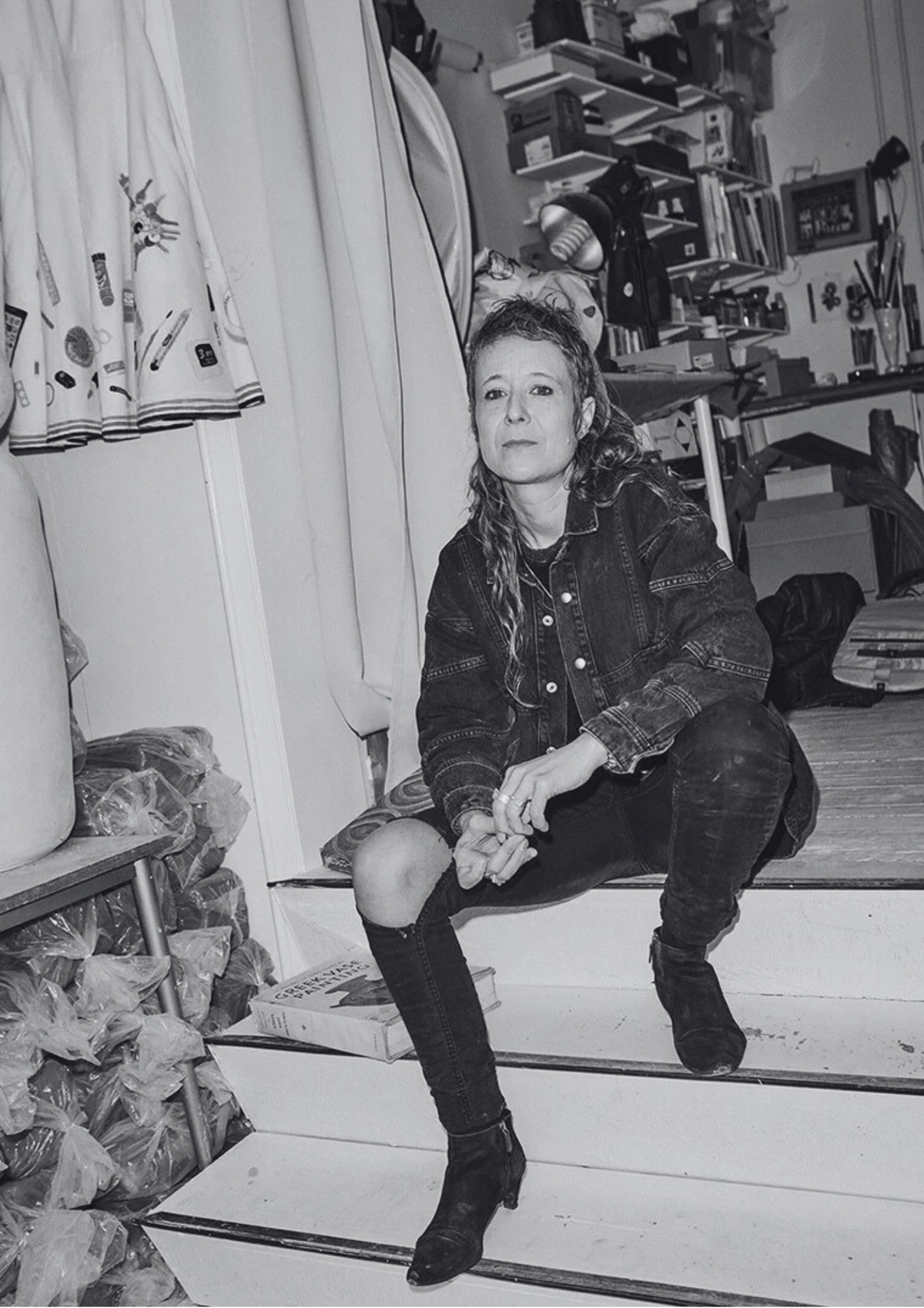 Rose Eken, Danish visual artist, sitting on stairs in her studio.