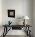 Art piece, lamp, and mirror on a rustic wooden table