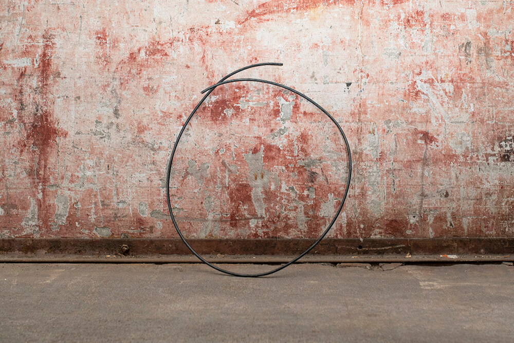 Black circular wire against a textured red and white wall background.