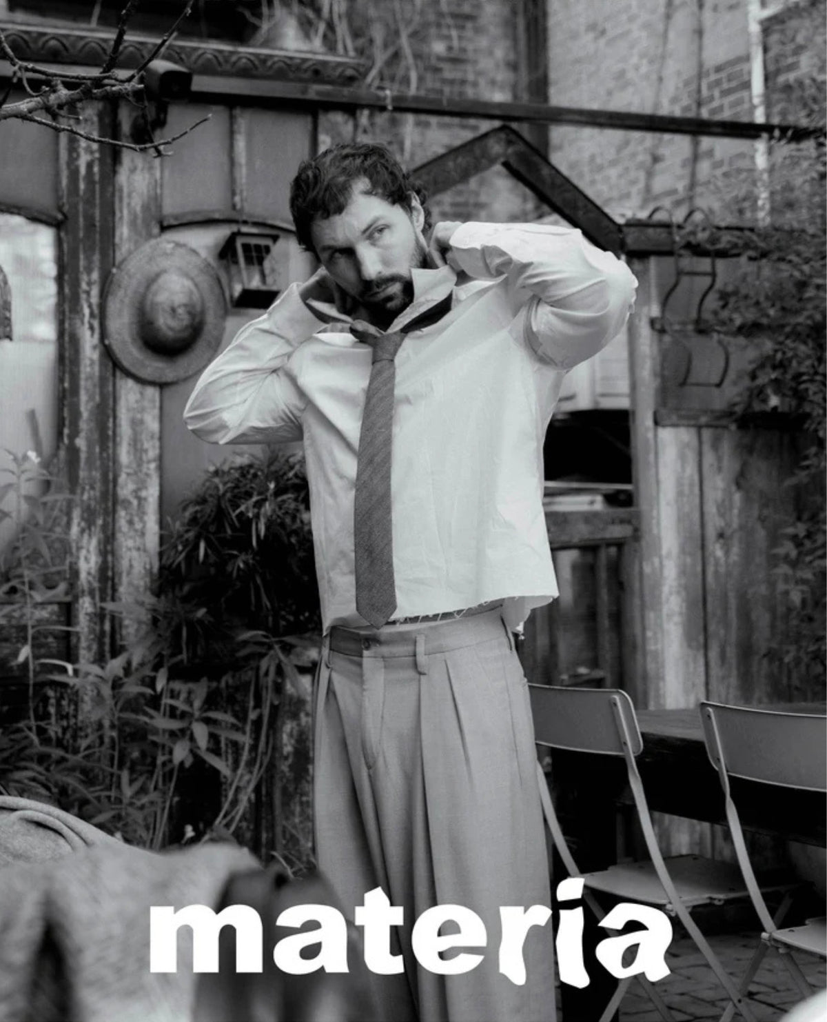 Andrés Reisinger in black and white adjusting his tie, with "materia" text.
